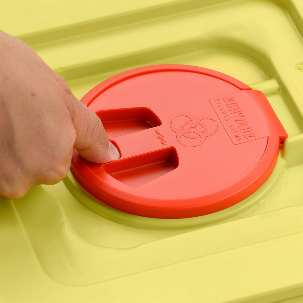 Käsi painaa keltaisen 12 litran Helmut Schwarz GmbH melijekt -kierrätysastian punaista kantta (20 kappaletta per laatikko), jossa on biohazard-symboli ja kaiverrus SHARPMAX".